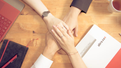 Mitarbeiter legen Hände aufeinander bei abra.sax, positive Entwicklung der Unternehmensberatung seit 1999